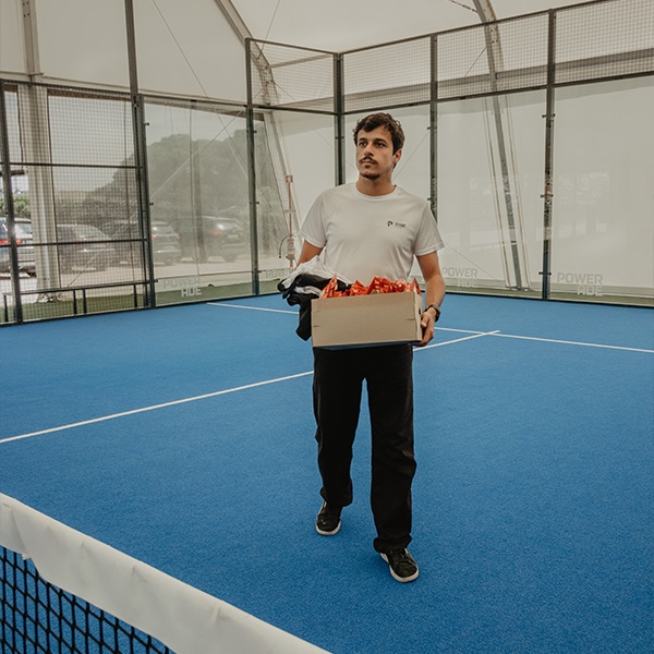 Man carrying a box on a padel court